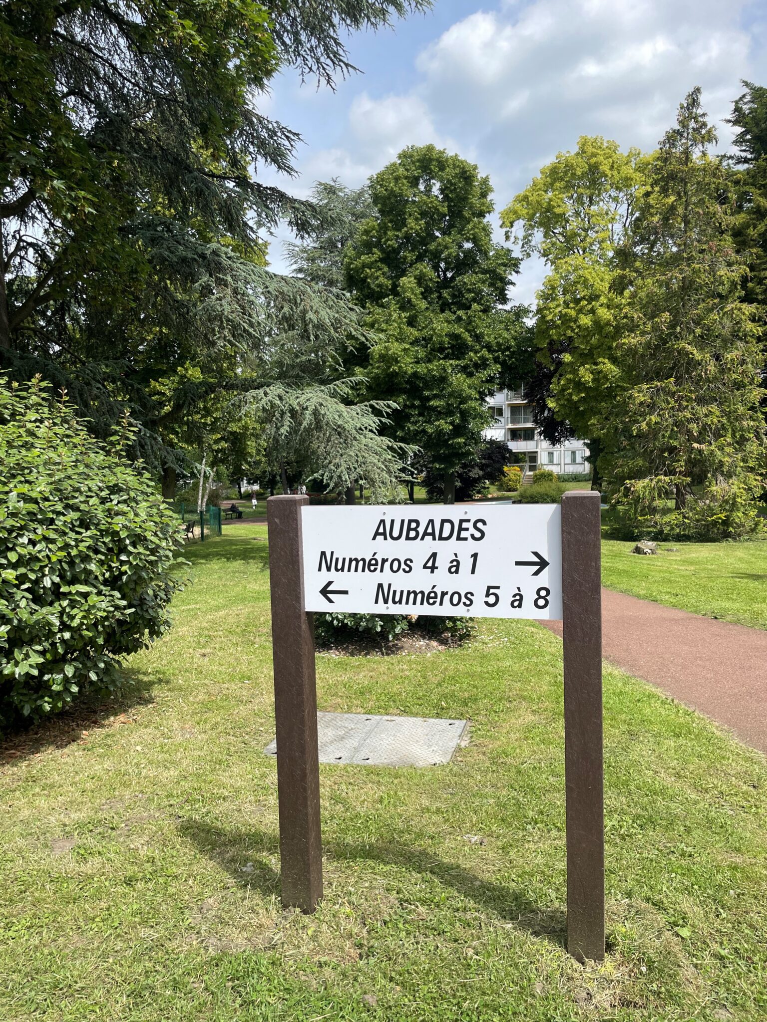 Panneau directionnel "Aubades" en parc verdoyant.